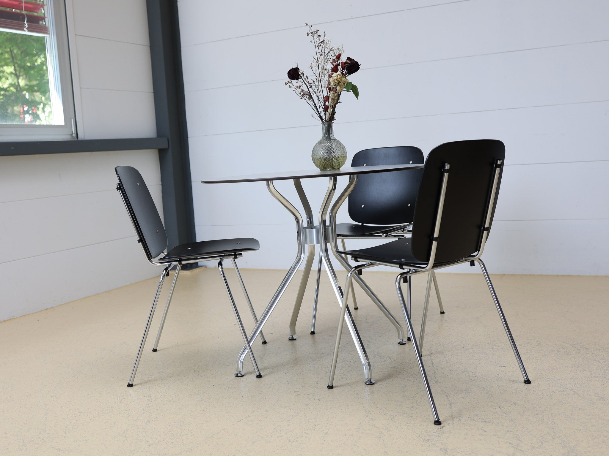 Rundtisch mit elegantem geschwungenem Chromgestell und grauer Tischplatte