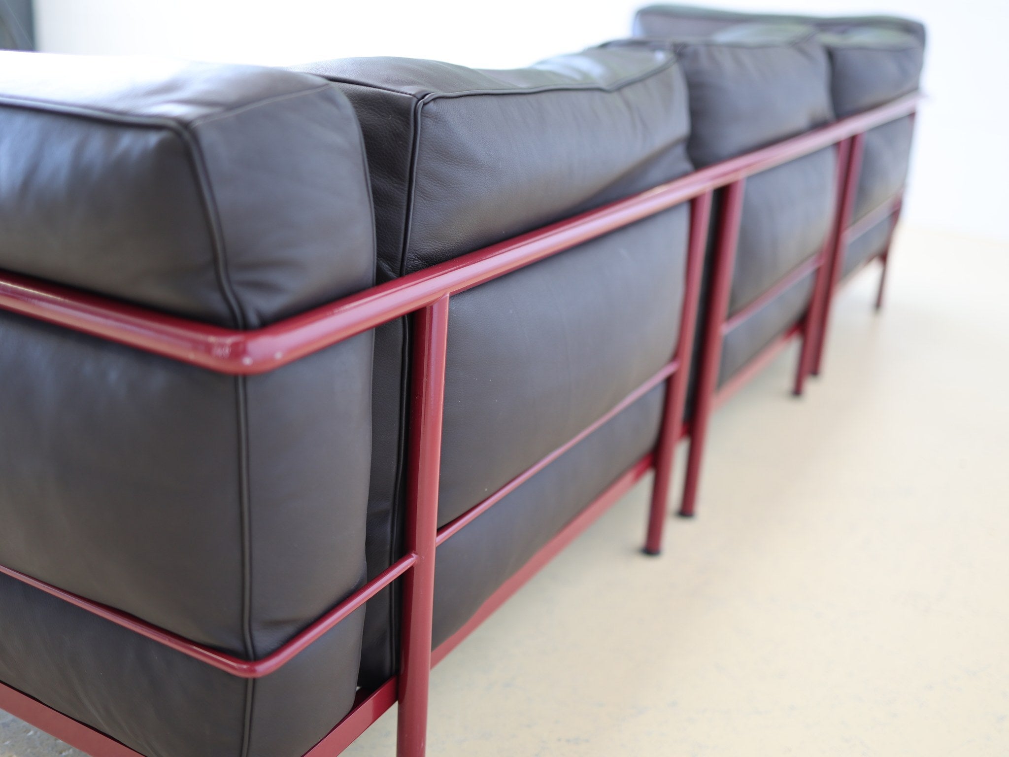 Cassina LC3 Drei-Sitzer – Rückansicht mit bordeauxrotem Stahlgestell